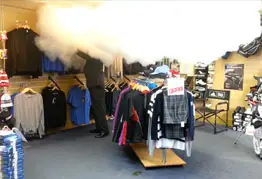 Photo of shop floor with clothes on hanging rails and thick white mist coming down from ceiling.