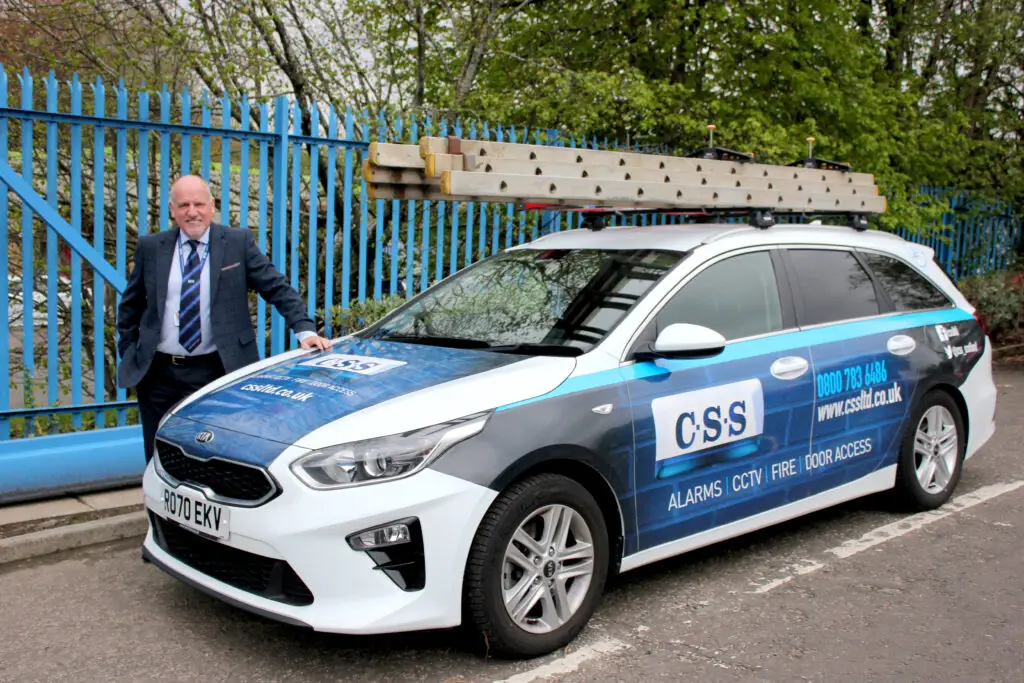 Photo of Paul Connelly standing smiling and resting his left hand on the bonnet of a CSS branded car.