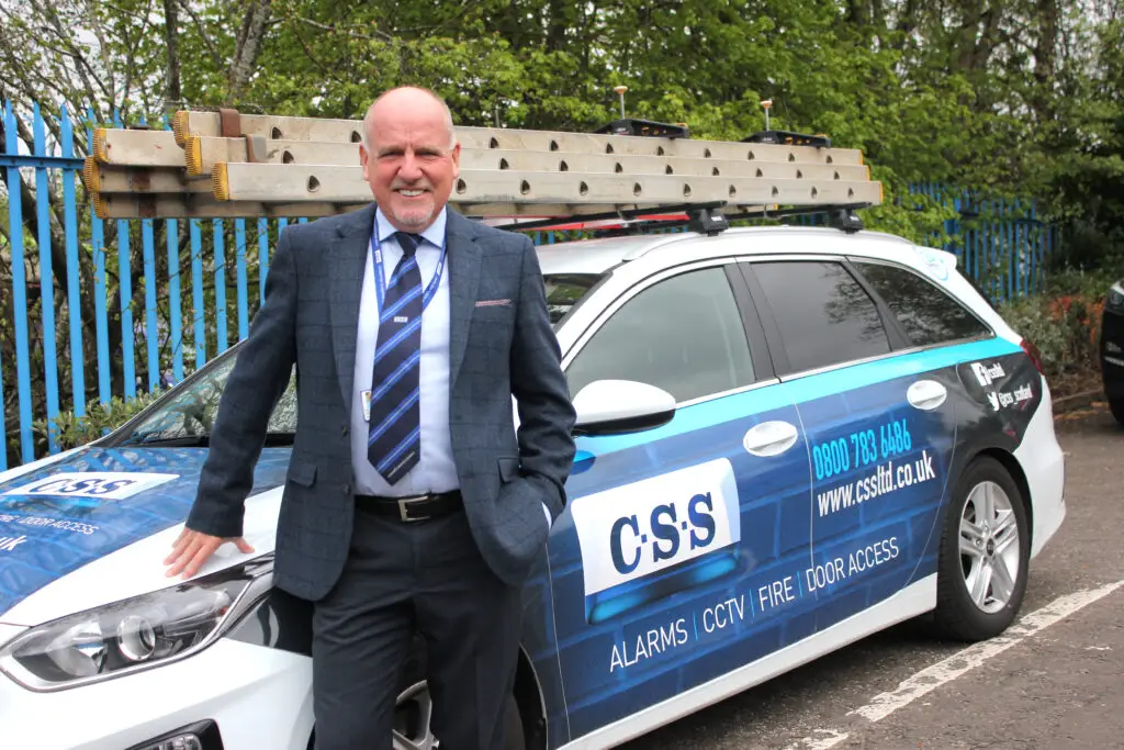 Photo of Paul Connelly standing smiling and resting his right hand on the bonnet of a CSS branded car.