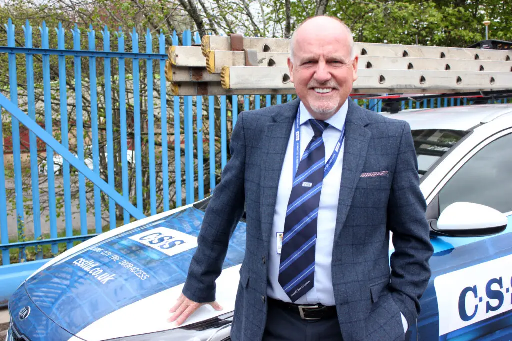 Photo of Paul Connelly standing smiling and resting his right hand on the bonnet of a CSS branded car.
