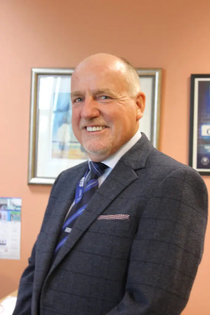 Photo of Paul Connelly standing smiling in his office.