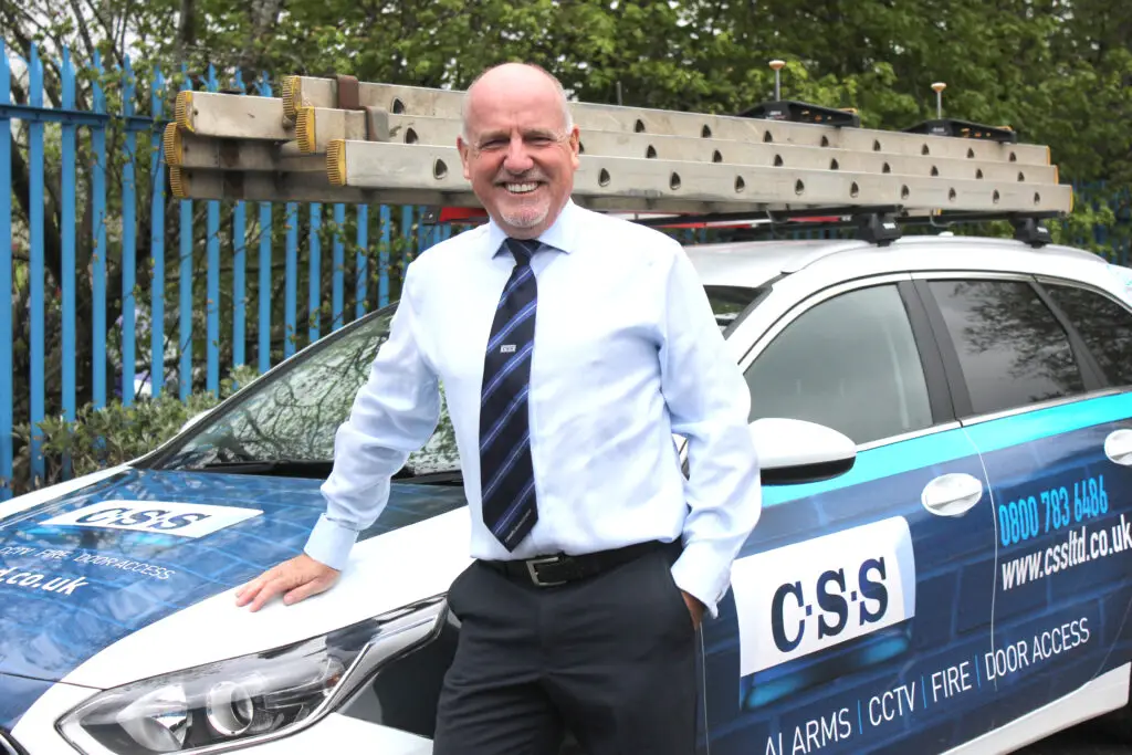 Photo of Paul Connelly standing smiling and resting his right hand on the bonnet of a CSS branded car.