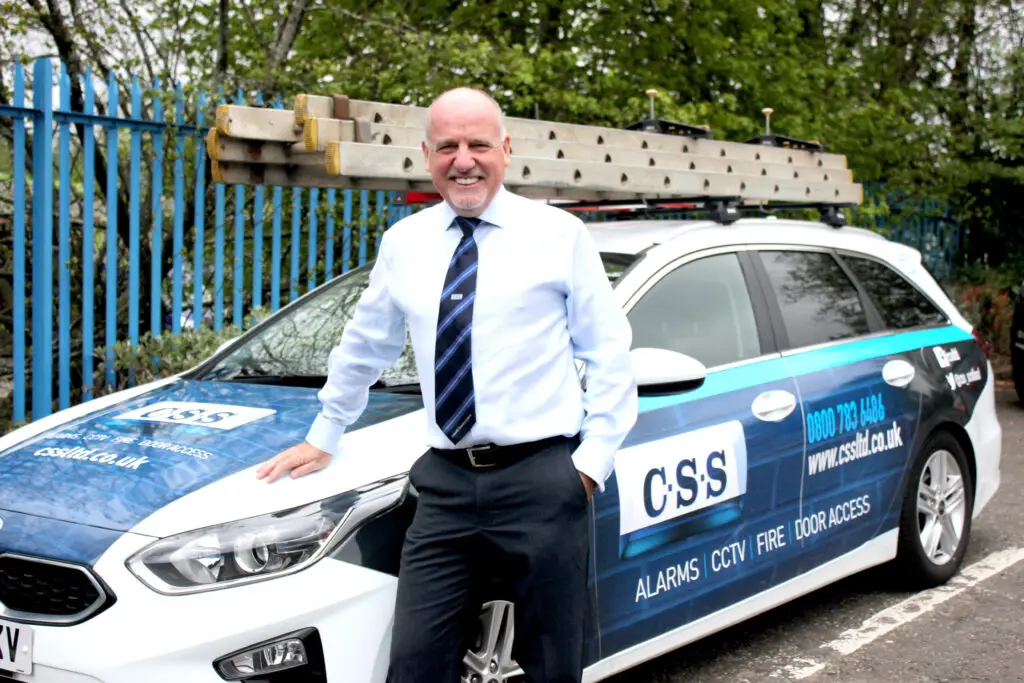 Photo of Paul Connelly standing smiling and resting his right hand on the bonnet of a CSS branded car.