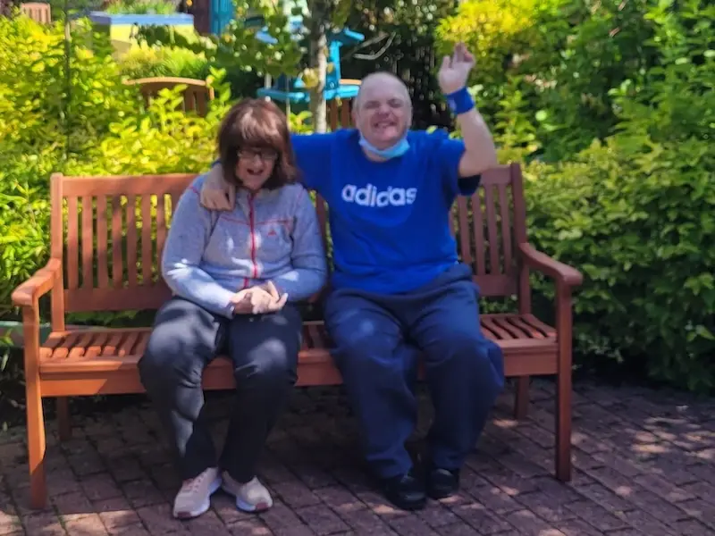 The Sense Scotland garden with two smiling people sitting on a bench on a sunny day